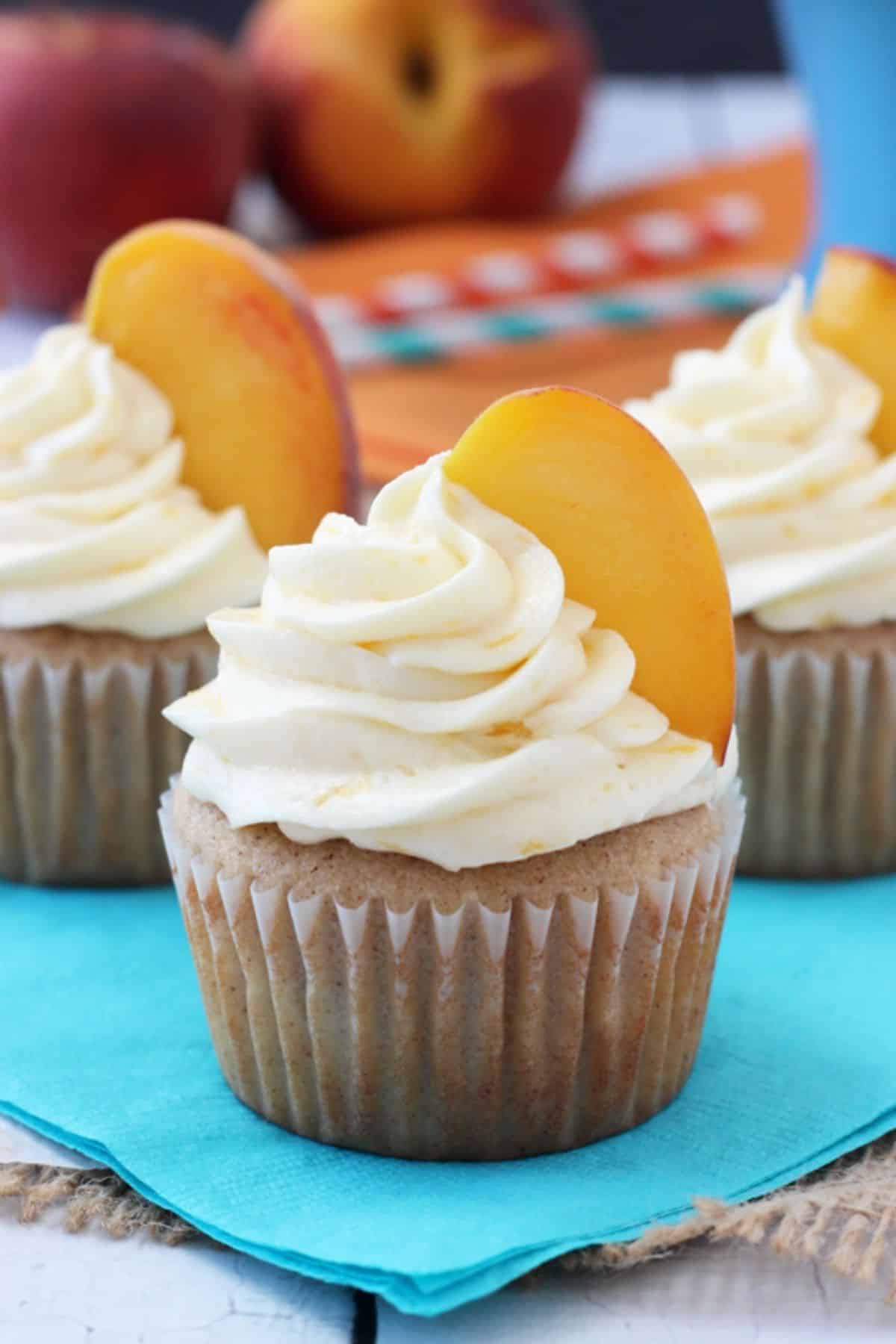 Close up of a peach pie cupcake on a teal napkin.