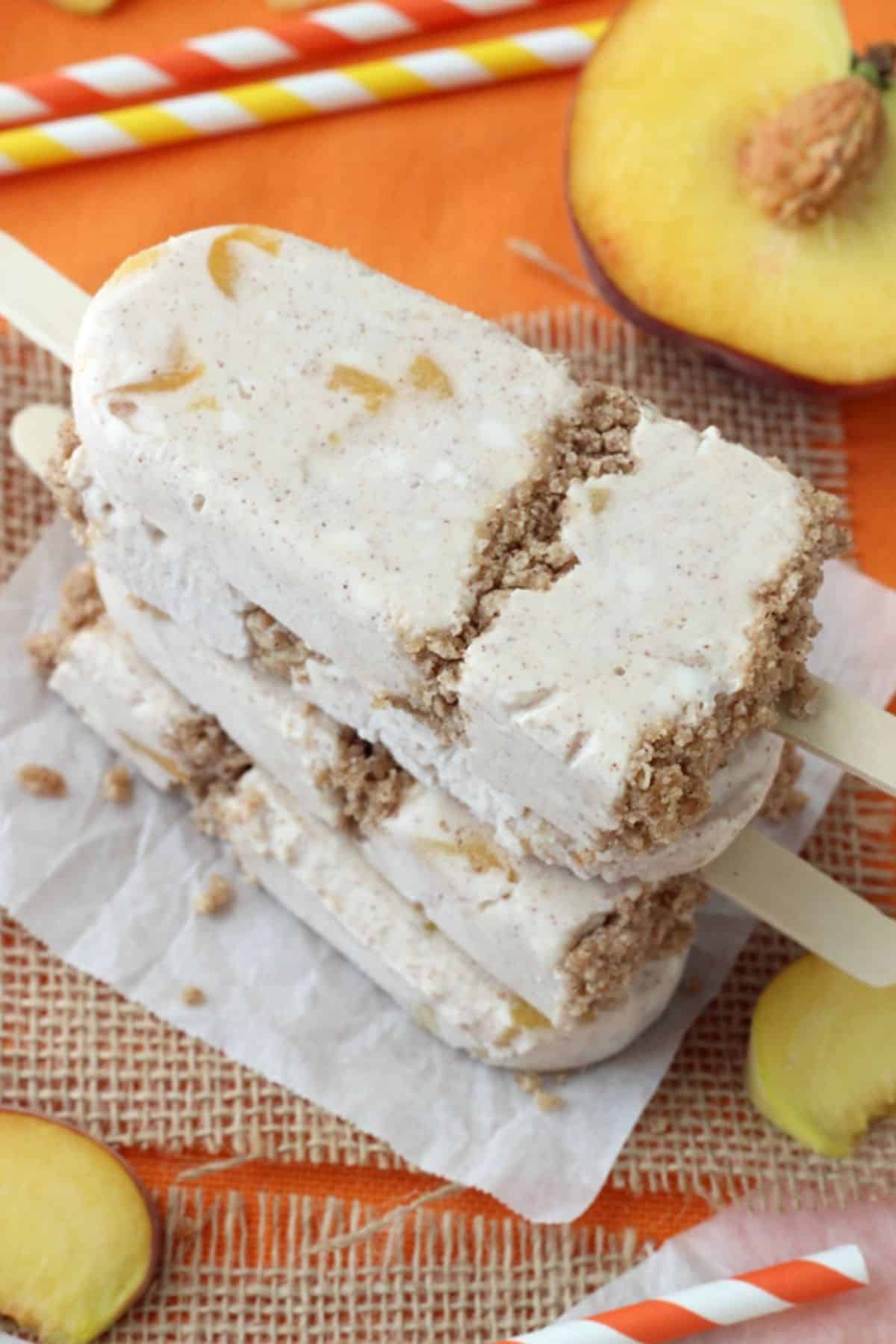 4 peach streusel popsicles stacked one on top of the other.