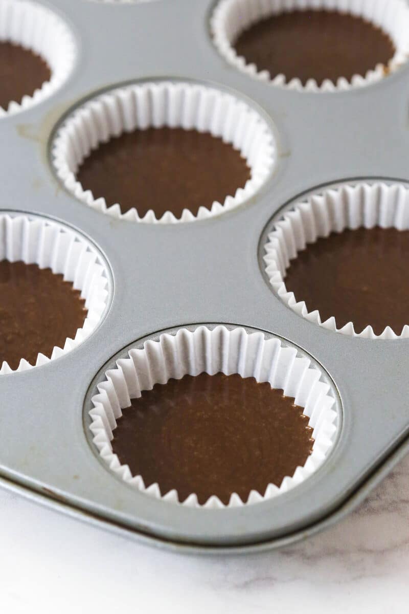 These peanut butter chocolate cupcakes are all about the classic flavor combo, with peanut butter buttercream on moist cupcakes. Cupcake liners half full with chocolate cupcake batter