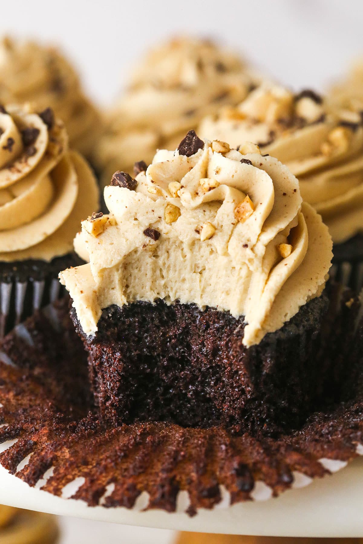 These peanut butter chocolate cupcakes are all about the classic flavor combo, with peanut butter buttercream on moist cupcakes. A peanut butter chocolate cupcake with the wrapped pulled down and a bite missing to show the inside
