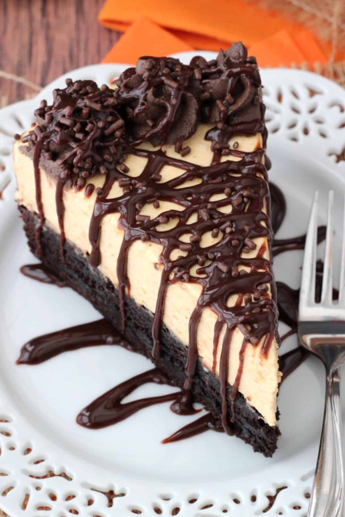 Close up of the top of a slice of pumpkin chocolate brownie cheesecake on a small white plate.
