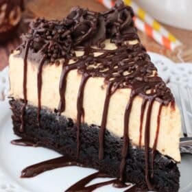 Close up of a slice of pumpkin chocolate brownie cheesecake on a small white plate.