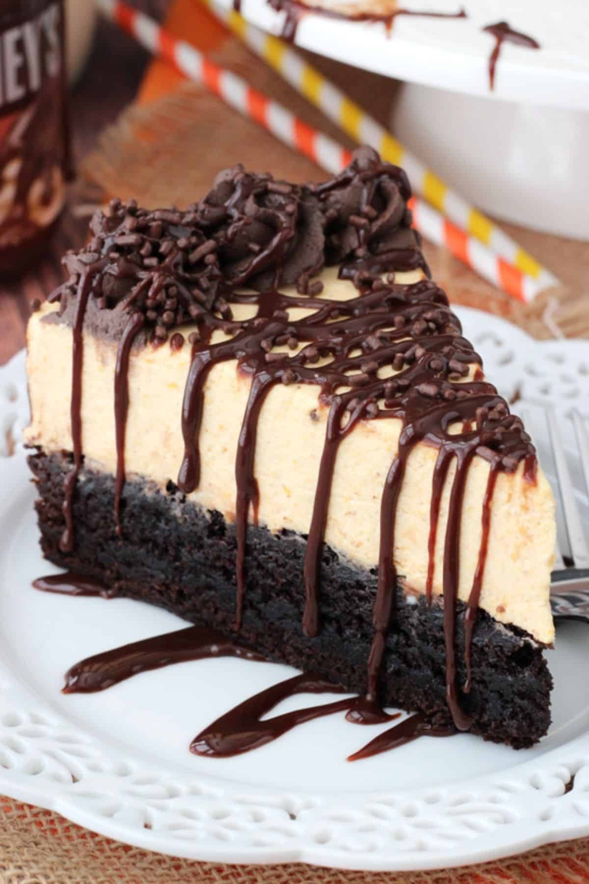 Close up of a slice of pumpkin chocolate brownie cheesecake on a small white plate.