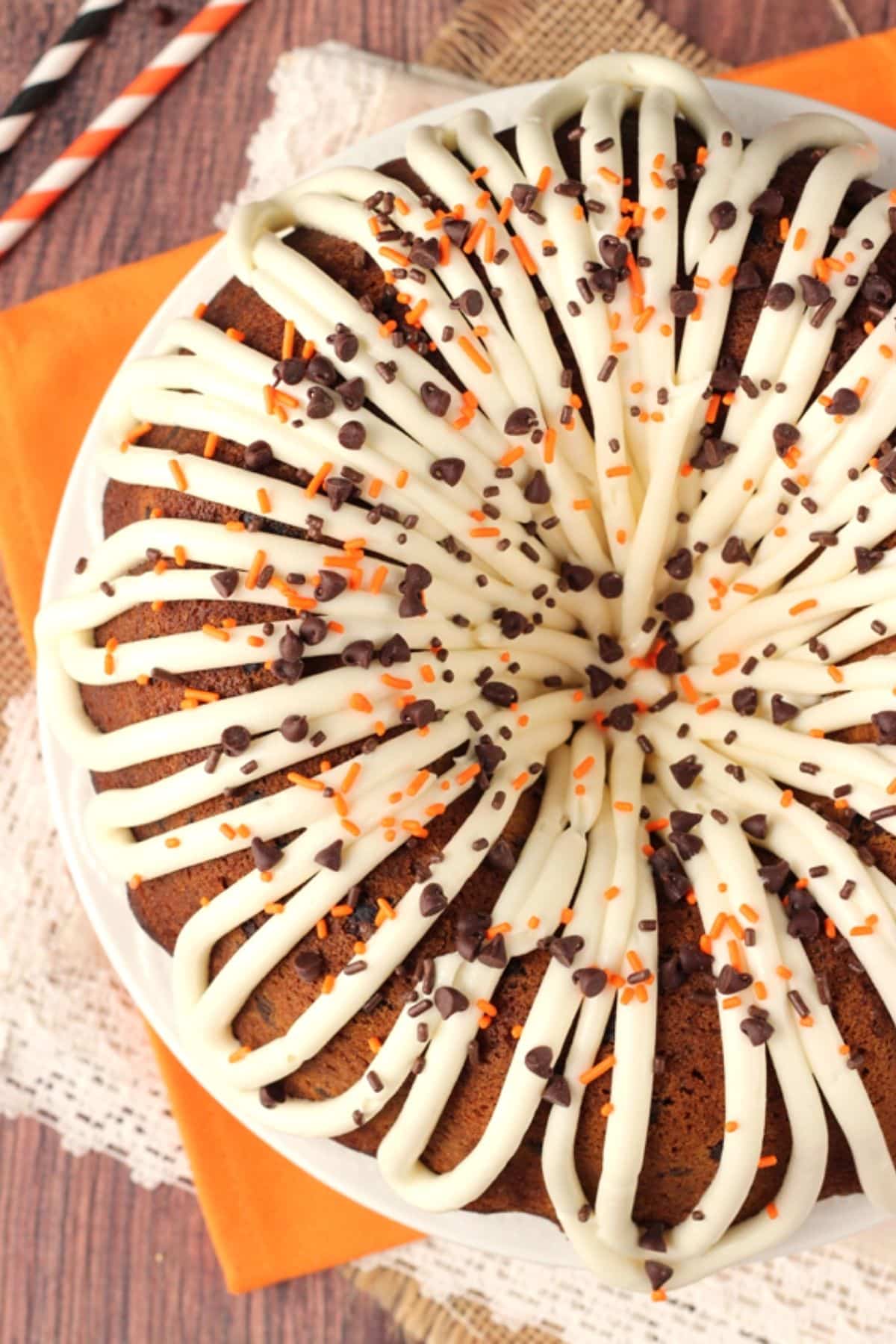 This pumpkin bundt cake with chocolate chips is soft, moist, and full of fall spices and gooey chocolate. It's perfect for Thanksgiving! Overhead shot of a frosted and decorated pumpkin chocolate chip bundt cake.