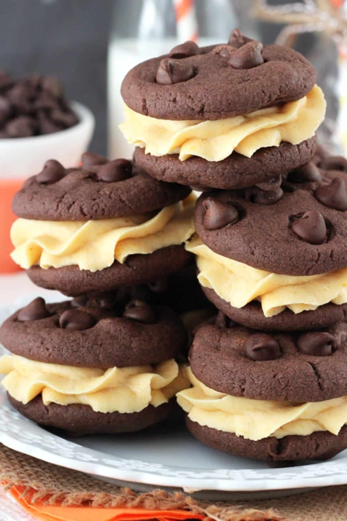 Pumpkin Chocolate Chip Cookie Sandwiches Close up of a pile of pumpkin chocolate chip cookie sandwiches on a white plate.