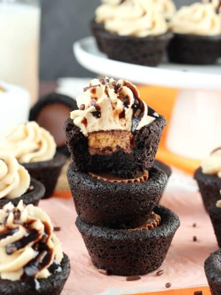 A stack of 3 Reese's chocolate cookie cups with a bite taken out of the top cookie.