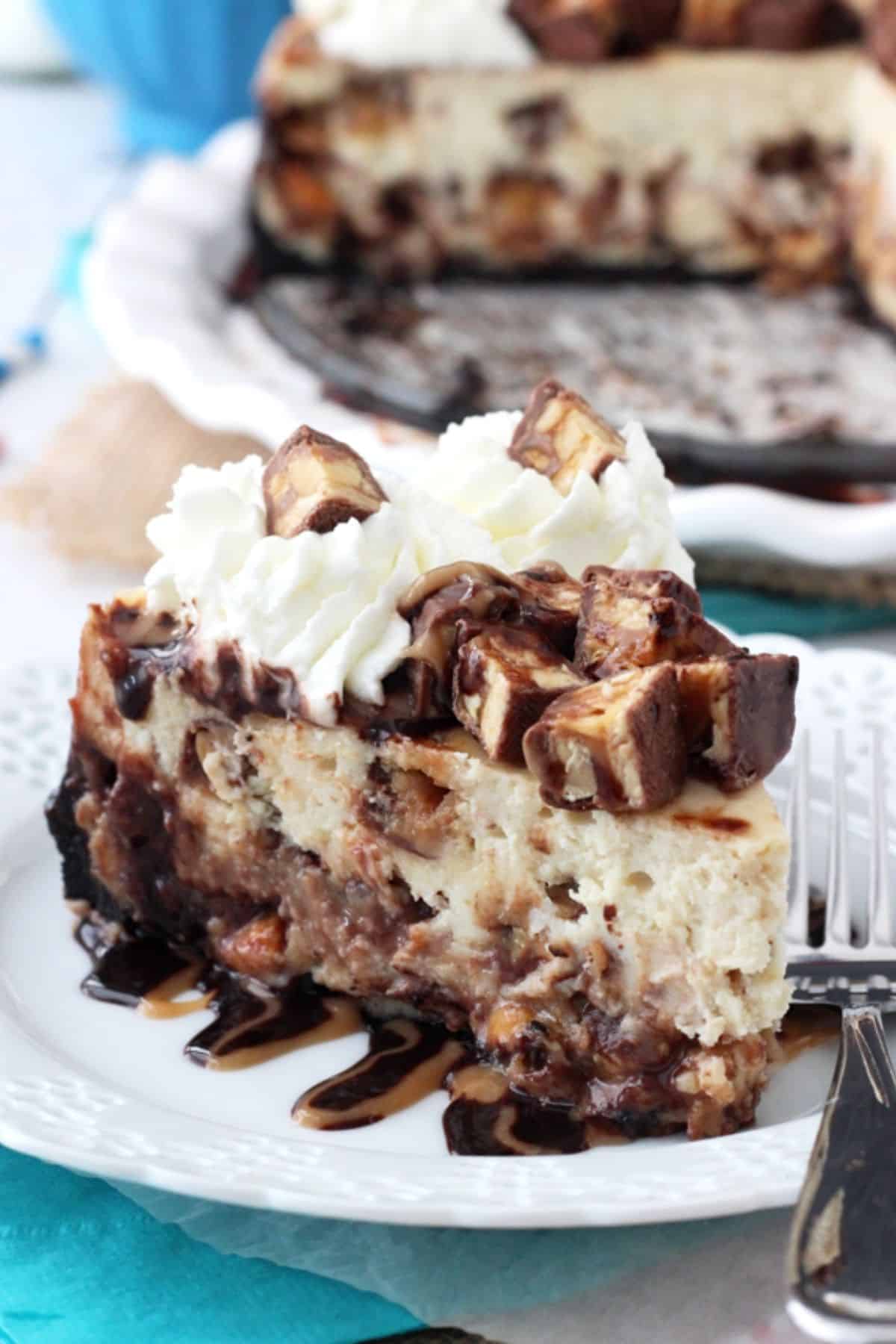 Close up of a Snickers cheesecake on a white plate.