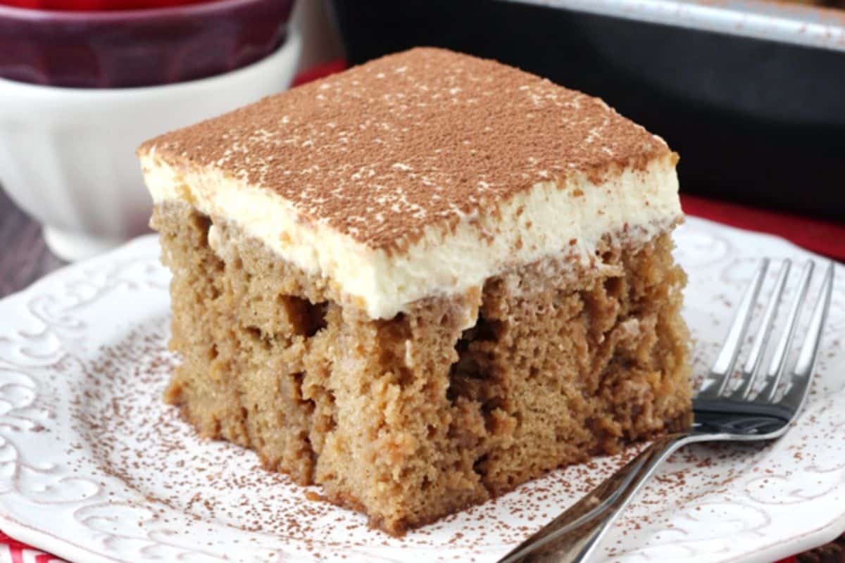 Close up of a slice of tiramisu poke cake on a small white plate.