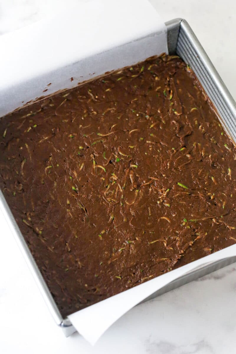 These zucchini brownies are not only quick and easy to make, they have the perfect super dense and fudgy texture. Zucchini brownie batter in a square pan