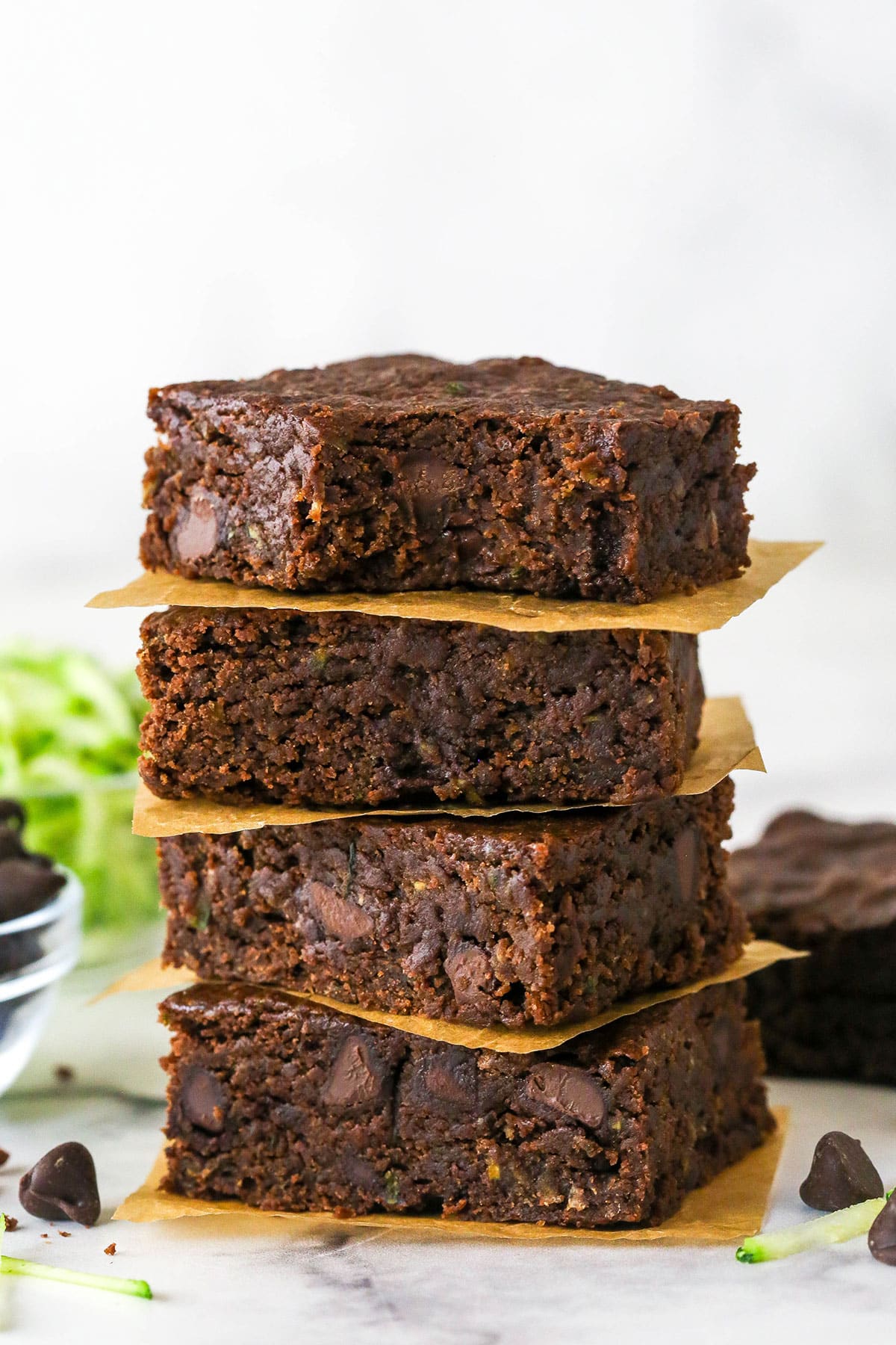 These zucchini brownies are not only quick and easy to make, they have the perfect super dense and fudgy texture. Four zucchini brownies stacked on each other, one with a bite missing