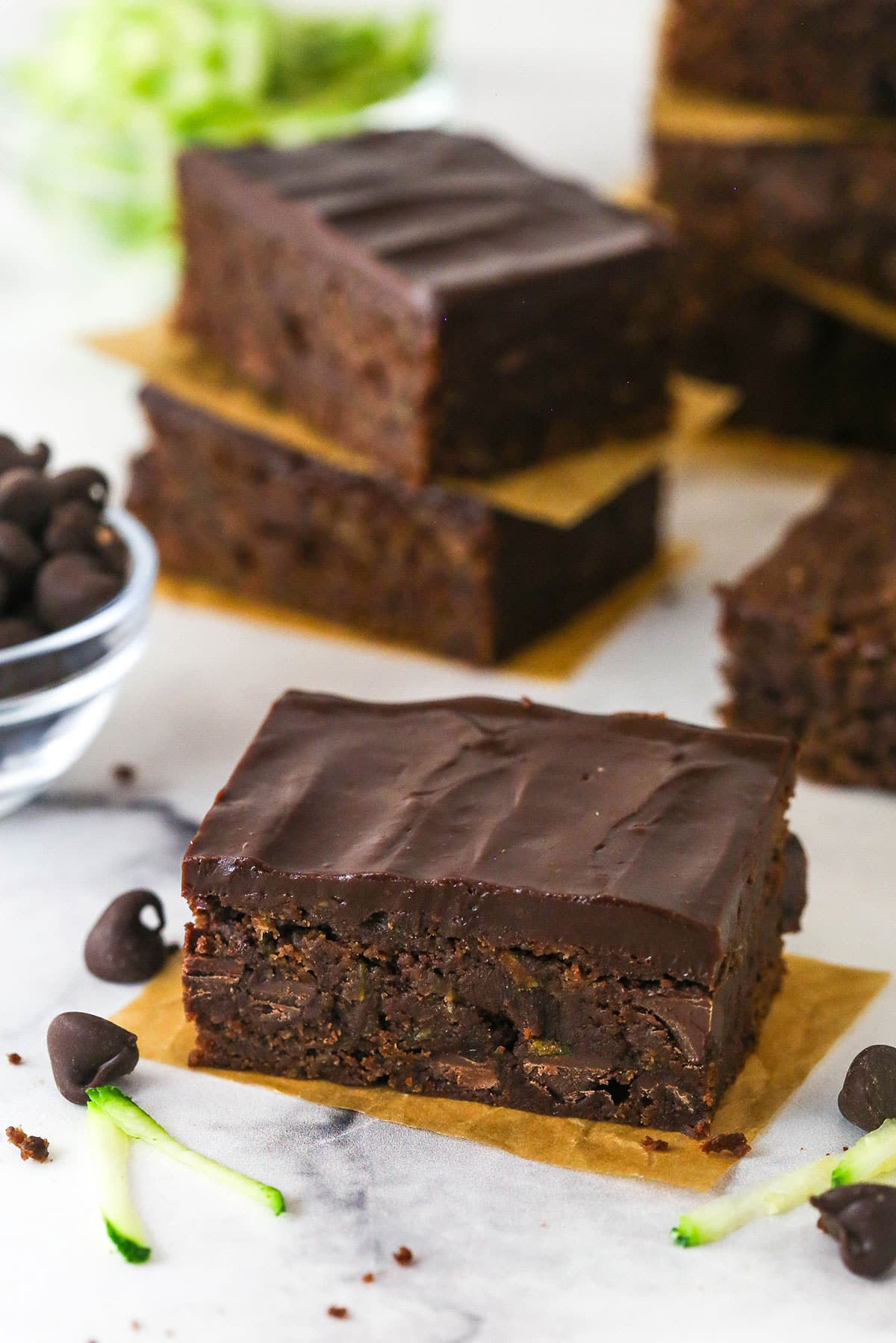 These zucchini brownies are not only quick and easy to make, they have the perfect super dense and fudgy texture. A zucchini brownie with chocolate ganache frosting on a napkin