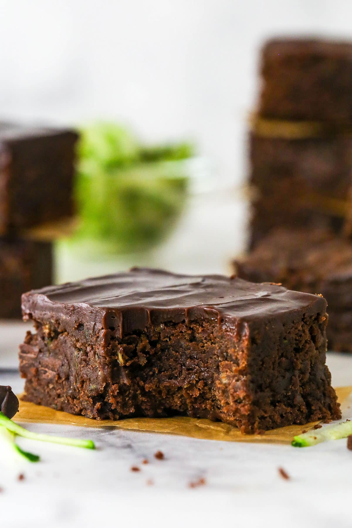 These zucchini brownies are not only quick and easy to make, they have the perfect super dense and fudgy texture. A fudgy zucchini brownie with a bite missing on a yellow napkin