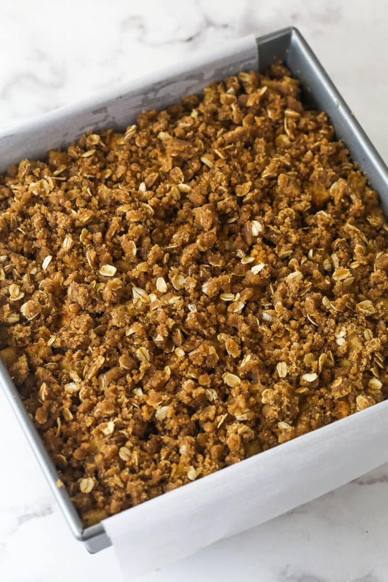 Apple pie bars offer all of the flavor of apple pie in a simple, easy-to-make bar, with shortbread crust, spiced apples, and crumble topping. Overhead view of apple pie bars in a square pan