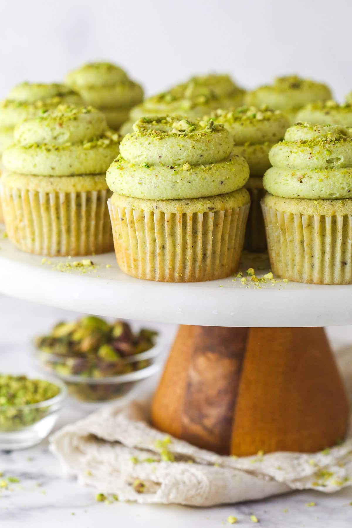 These pistachio cupcakes are full of real pistachios in the cupcakes and the buttercream, giving them their beautiful color and nutty flavor. Pistachio cupcakes on a cake stand