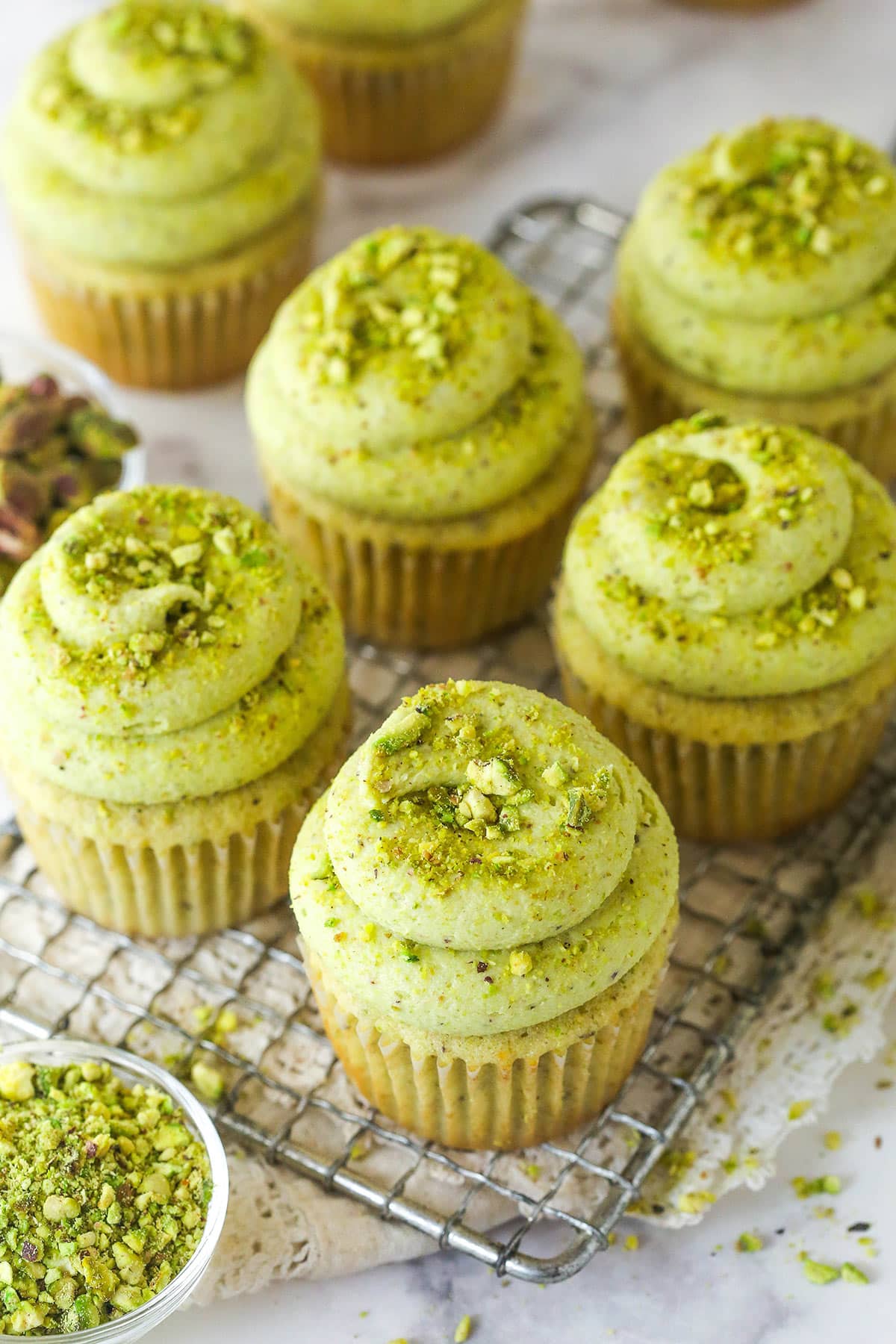 These pistachio cupcakes are full of real pistachios in the cupcakes and the buttercream, giving them their beautiful color and nutty flavor. Overhead view of pistachio cupcakes on a cooling rack