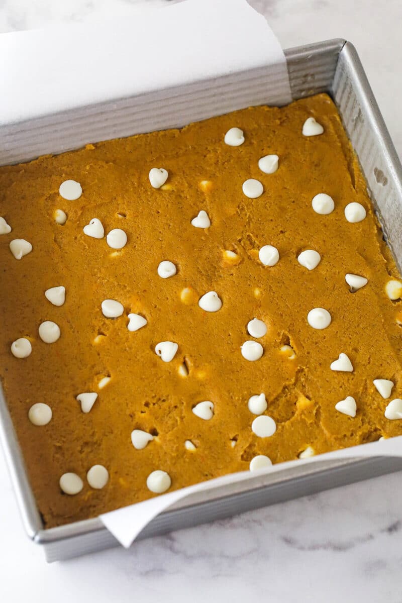 These pumpkin blondies are perfectly soft (but not cakey!) and chewy, dotted with white chocolate chips and full of fall flavors. Overhead view of pumpkin blondie batter in a square pan