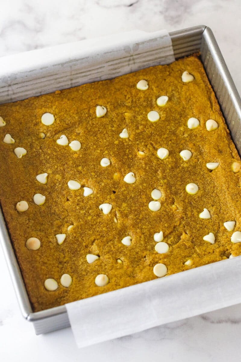 These pumpkin blondies are perfectly soft (but not cakey!) and chewy, dotted with white chocolate chips and full of fall flavors. Overhead view of a square pan of pumpkin blondies