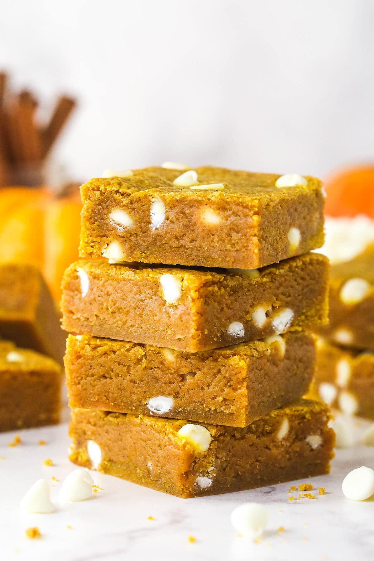 These pumpkin blondies are perfectly soft (but not cakey!) and chewy, dotted with white chocolate chips and full of fall flavors. Four pumpkin blondies stacked on each other