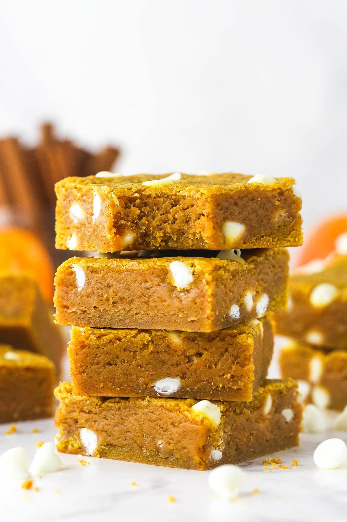 These pumpkin blondies are perfectly soft (but not cakey!) and chewy, dotted with white chocolate chips and full of fall flavors. A stack of four pumpkin blondies, the top one missing a bite
