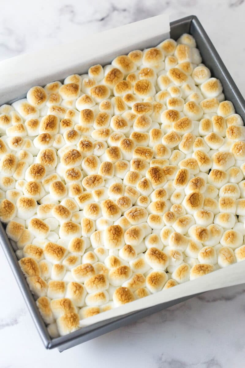 These s'mores brownies have all the classic flavors, with a graham cracker crust, fudgy brownies, ganache, and toasted marshmallows. Toasted mini marshmallows on top of brownies in a square pan