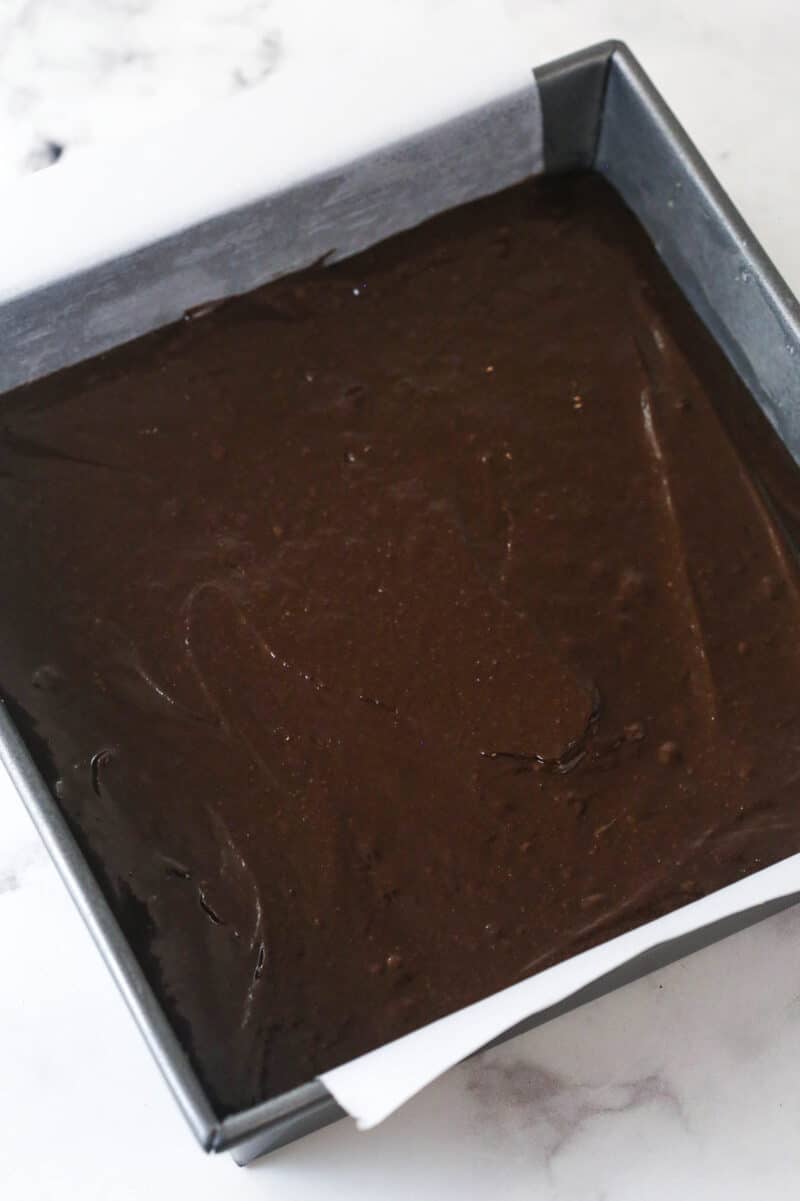 These s'mores brownies have all the classic flavors, with a graham cracker crust, fudgy brownies, ganache, and toasted marshmallows. Brownie batter in a square pan