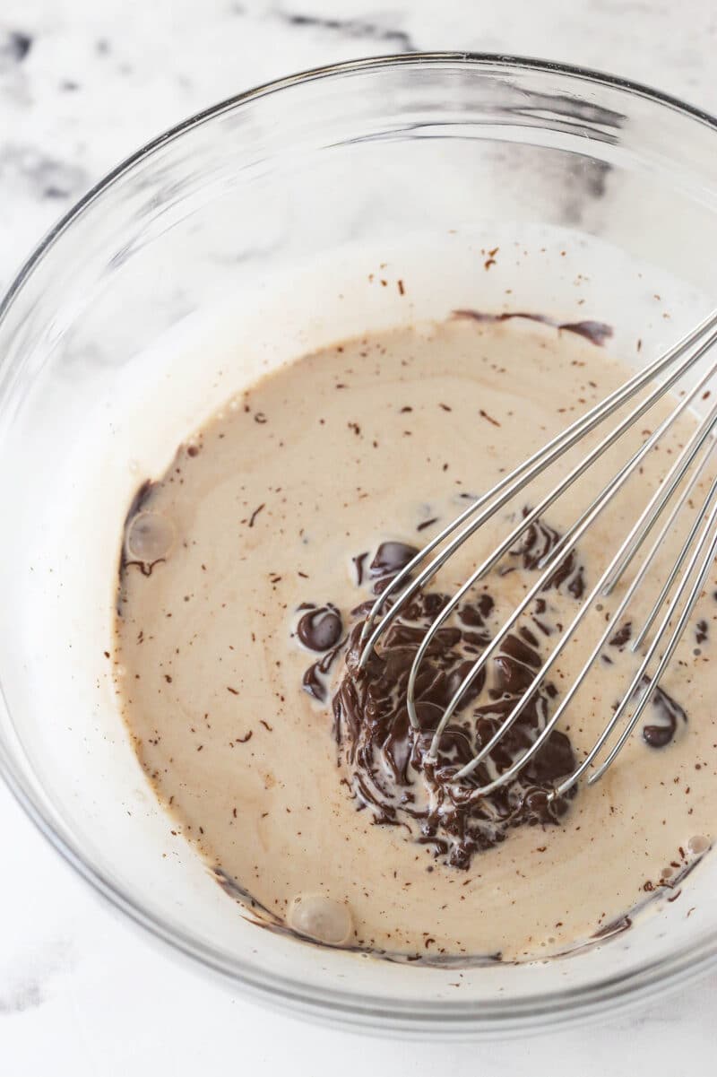 These s'mores brownies have all the classic flavors, with a graham cracker crust, fudgy brownies, ganache, and toasted marshmallows. Chocolate chips and heavy cream in a bowl