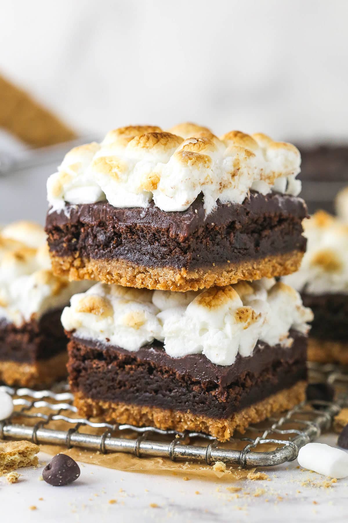 These s'mores brownies have all the classic flavors, with a graham cracker crust, fudgy brownies, ganache, and toasted marshmallows. Two s'mores brownies stacked on top of each other