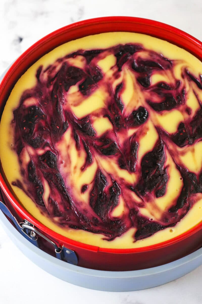 baked cheesecake with berry swirl on top in springform pan