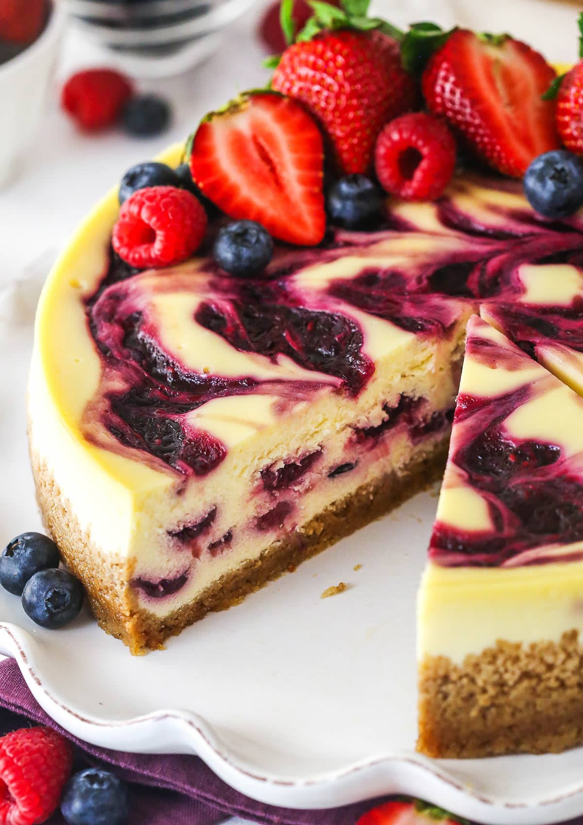 triple berry cheesecake with a slice removed to see inside