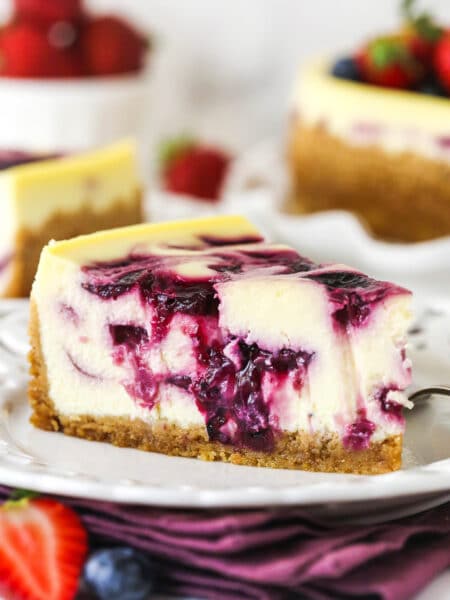 slice of triple berry cheesecake on white plate