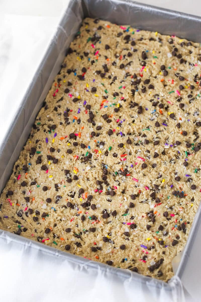 Brownie cookie dough ice cream sandwiches combine three favorites in one, with a few key ingredients to ensure they stay soft. Chocolate chip cookie dough spread in a pan