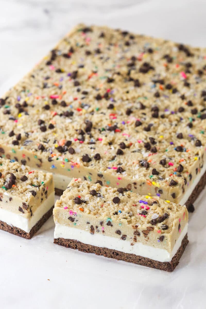 Brownie cookie dough ice cream sandwiches combine three favorites in one, with a few key ingredients to ensure they stay soft. Two brownie cookie dough ice cream sandwiches sliced off from the rest