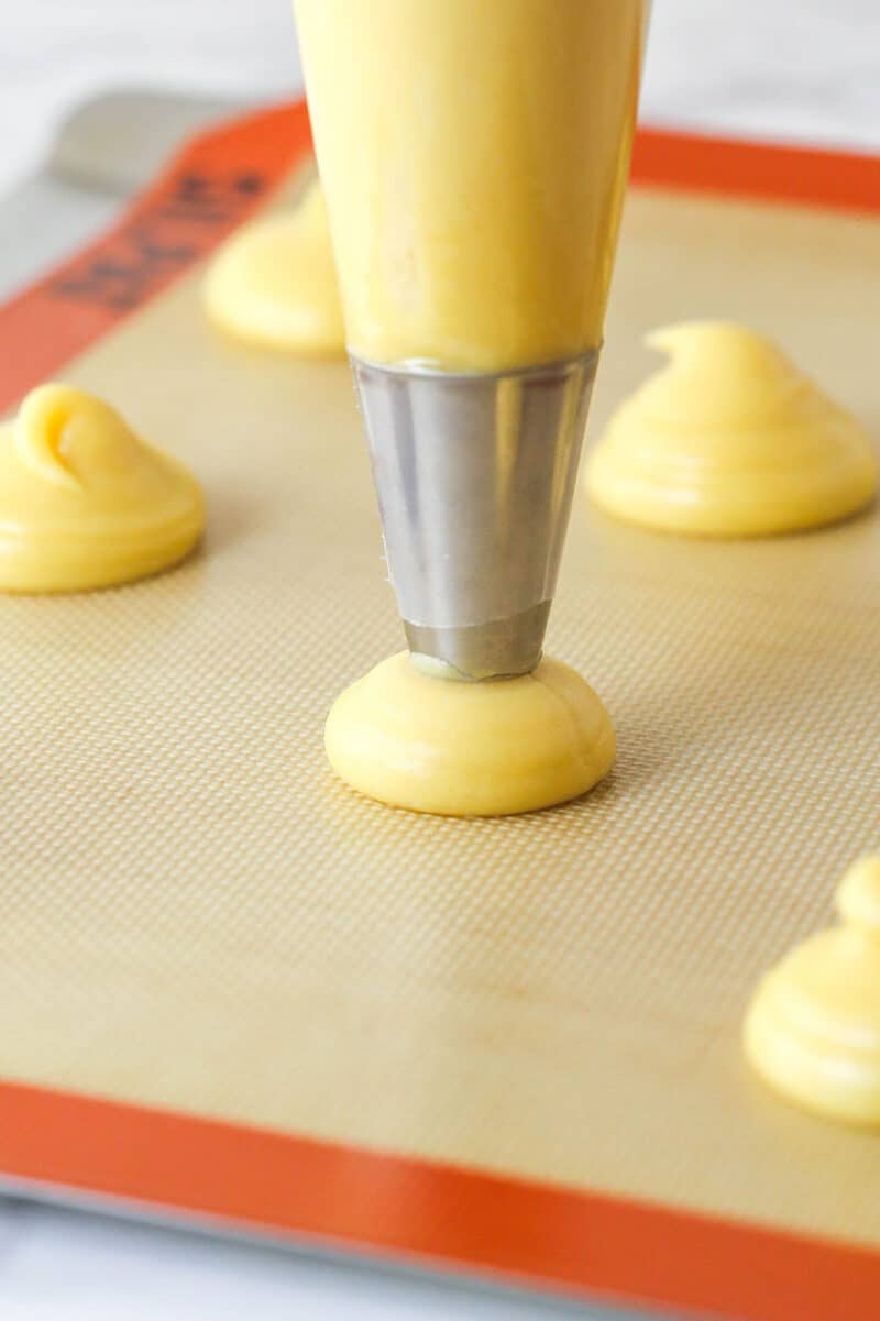 Master making cream puffs fit for a bakery and perfect for sharing with my in-depth tips and step-by-step photos. Piping choux pastry for puff pastry shells on a baking sheet