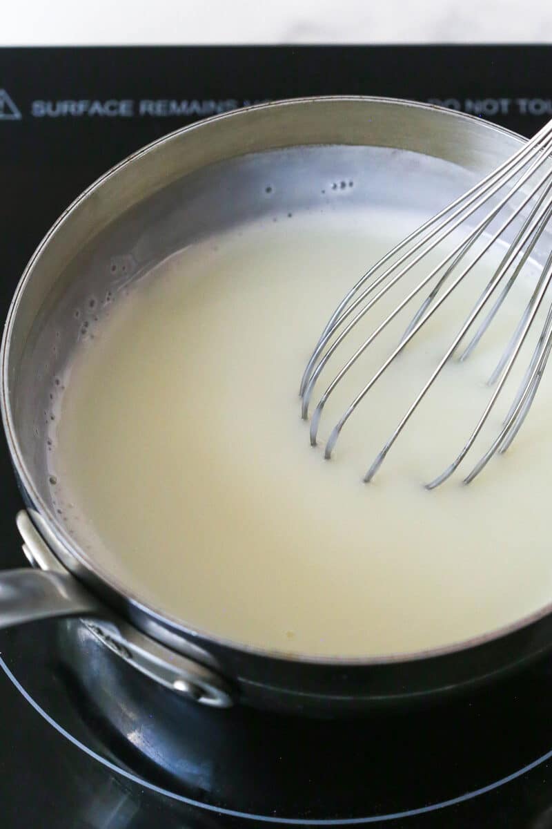 Master making cream puffs fit for a bakery and perfect for sharing with my in-depth tips and step-by-step photos. Whisking milk in a saucepan