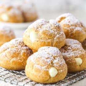 A pile of cream puffs on a cooking rack