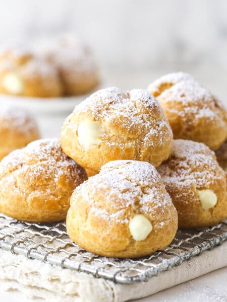 A pile of cream puffs on a cooking rack