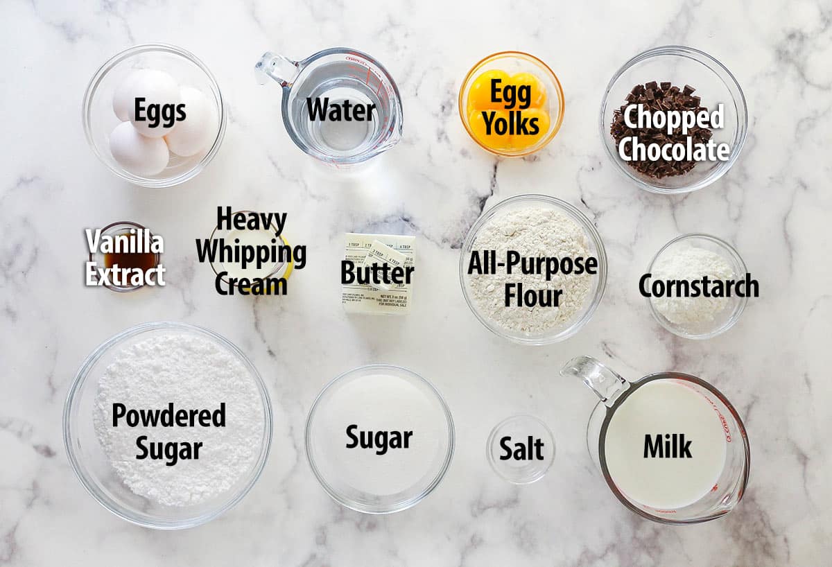 Mastering eclairs at home is easier than you think with my step-by-step photos and in-depth tips. Made with pastry cream & chocolate glaze. Overhead view of ingredients to make homemade eclairs