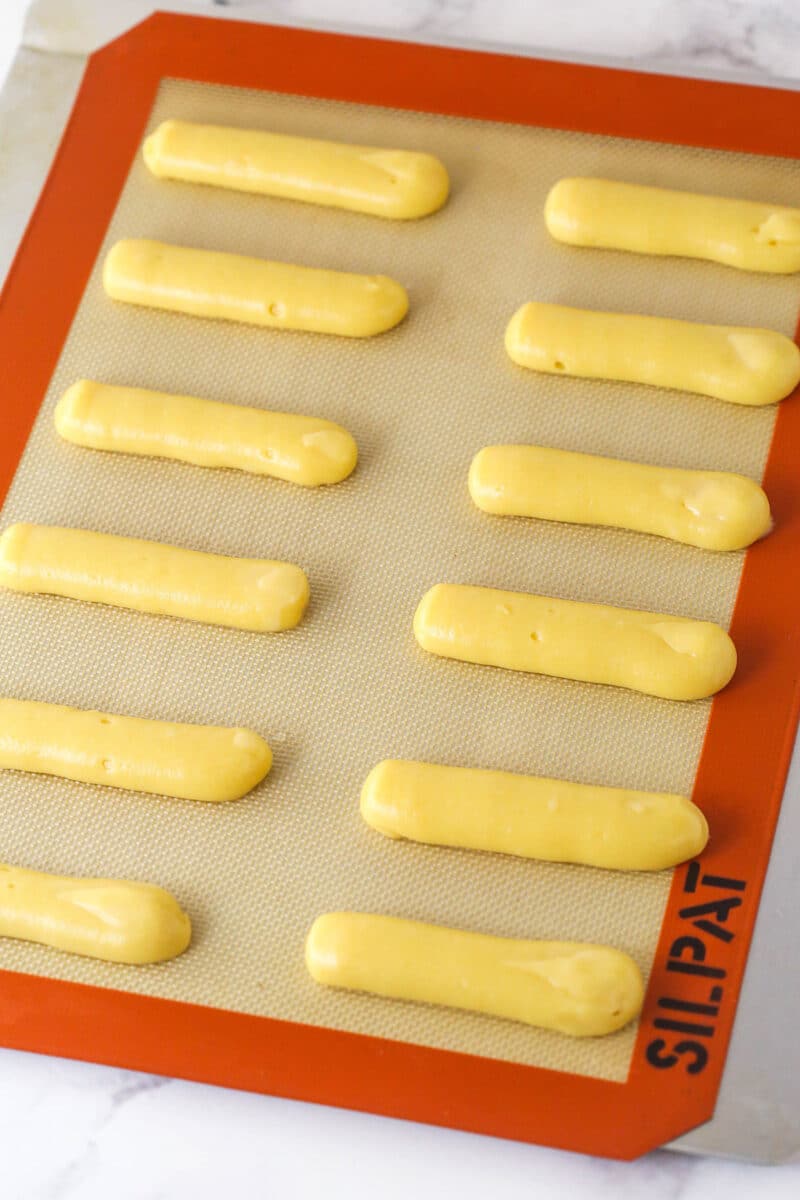 Choux pastry piped into long strips on a baking sheet