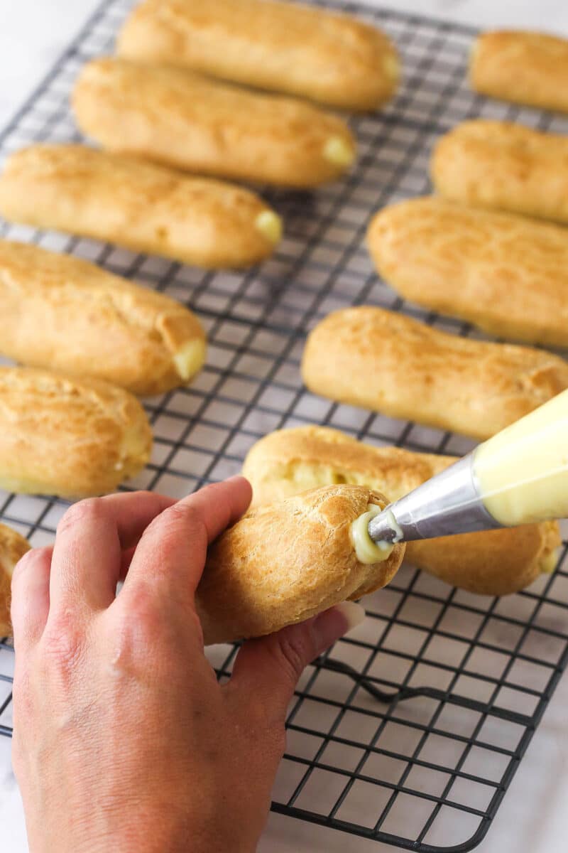 Mastering eclairs at home is easier than you think with my step-by-step photos and in-depth tips. Made with pastry cream & chocolate glaze. Filling eclair pastry shells with pastry cream