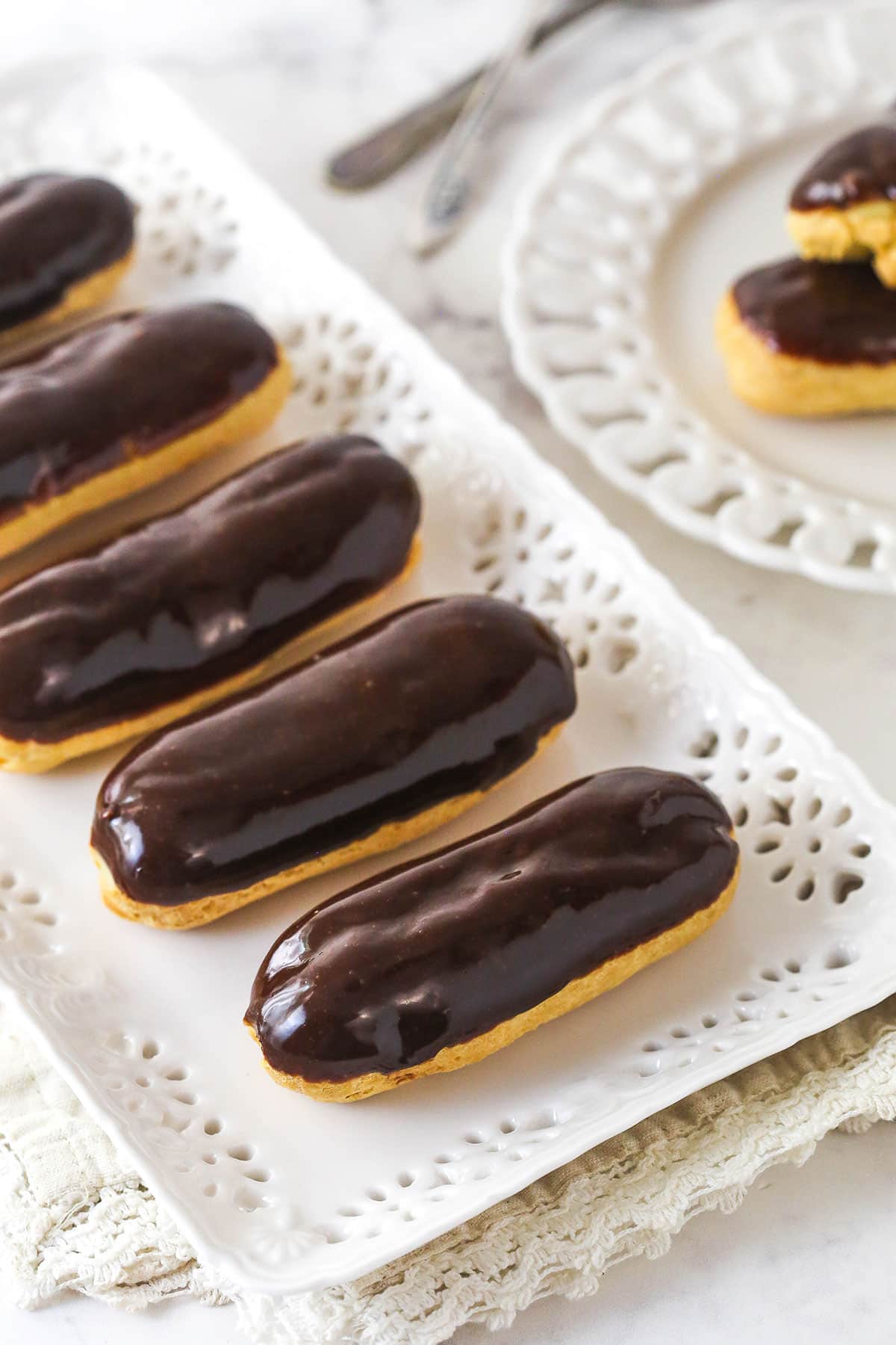 Mastering eclairs at home is easier than you think with my step-by-step photos and in-depth tips. Made with pastry cream & chocolate glaze. Overhead view of a tray of homemade eclairs