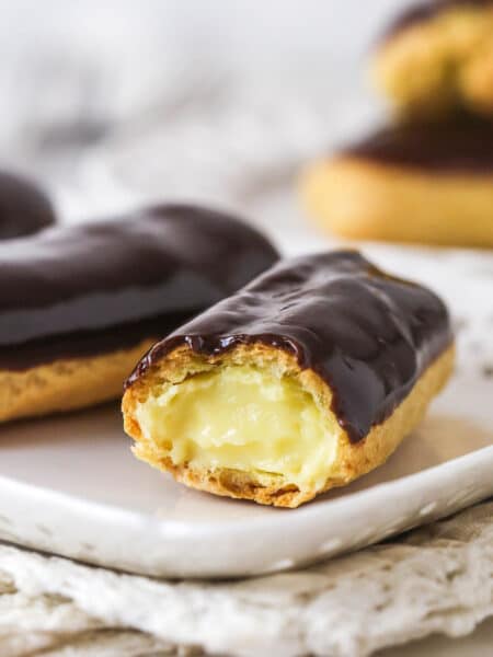 Homemade eclairs on a plate, one missing a bit to show the inside