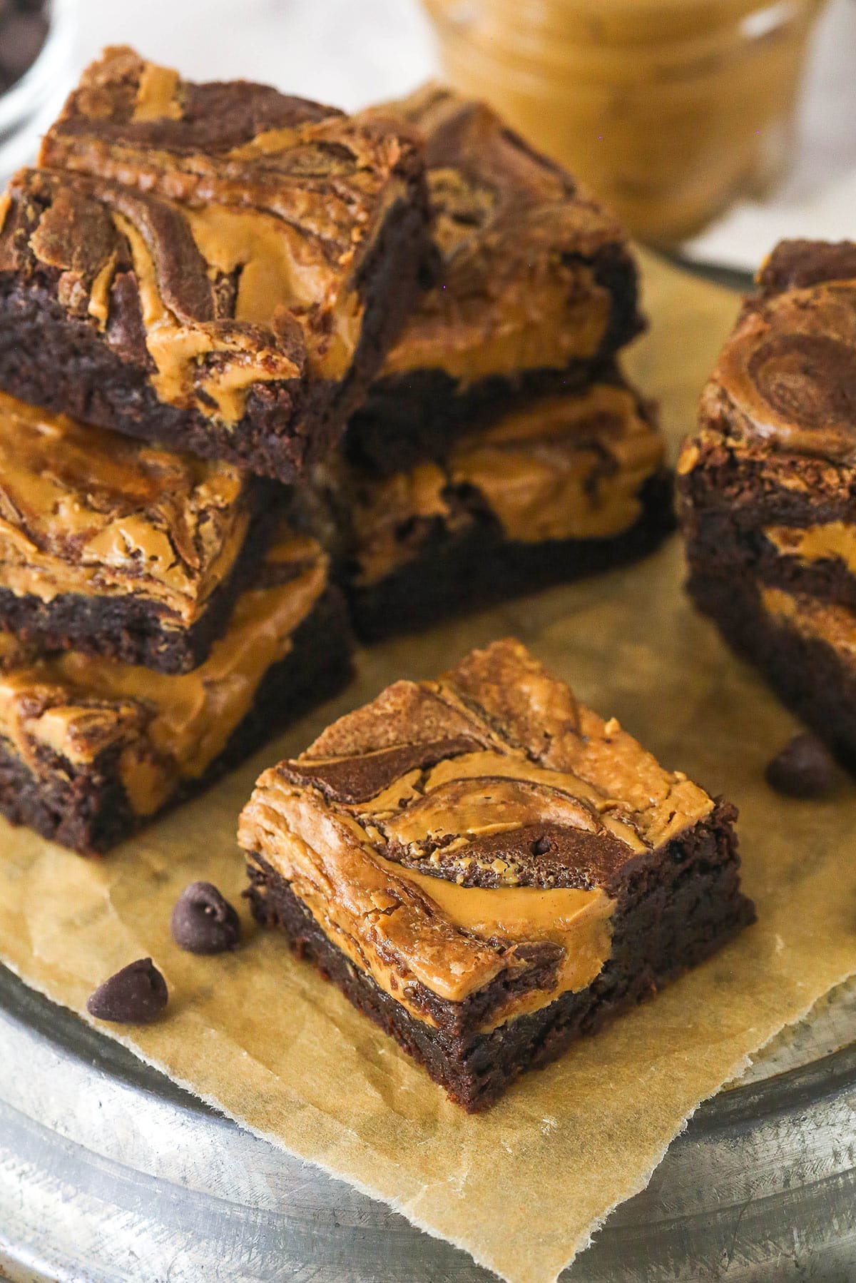 Creamy peanut butter is swirled into rich, chewy chocolate brownies in this easy Peanut Butter Brownies recipe. Angled overhead view of peanut butter brownies stacked on parchment paper