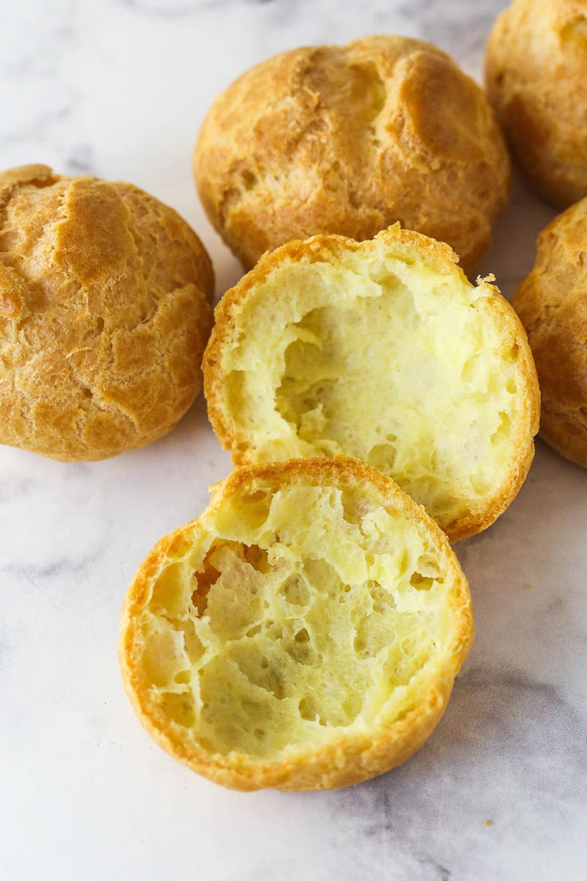Turn 6 ingredients into the perfect choux pastry base for eclairs, cream puffs, and more with these expert tips. Choux pastry shells on the counter, one cut in half to show the hollow inside.