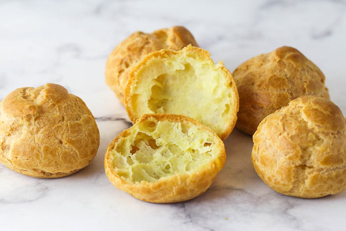 Turn 6 ingredients into the perfect choux pastry base for eclairs, cream puffs, and more with these expert tips. Choux pastry shells on the counter, one cut open to show the hollow insides