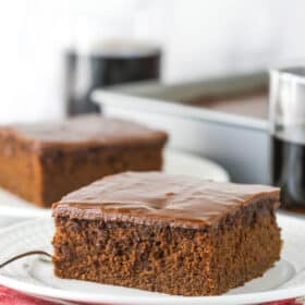 A slice of Coca Cola cake on a small white plate.