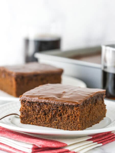A slice of Coca Cola cake on a small white plate.
