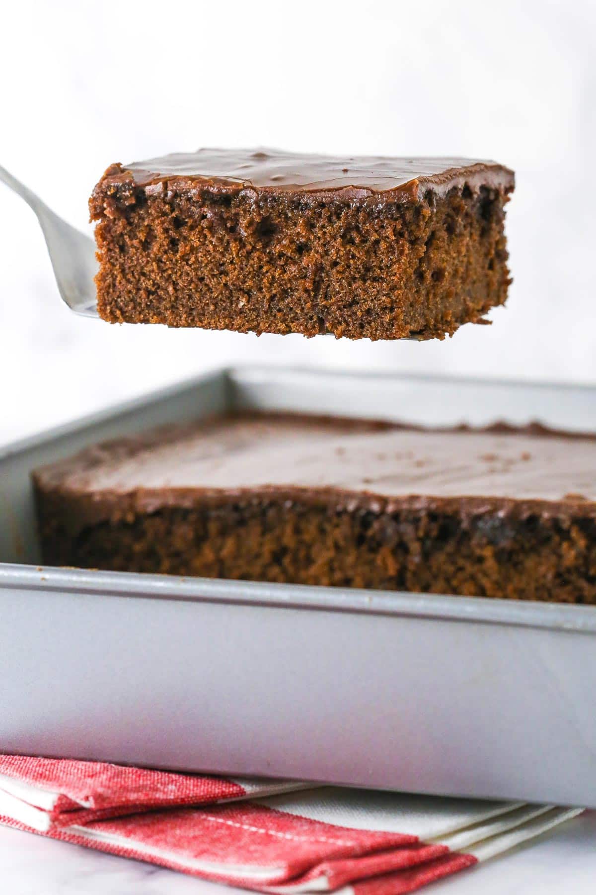 A slice of Coca Cola cake being lifted from the pan on a spatula.