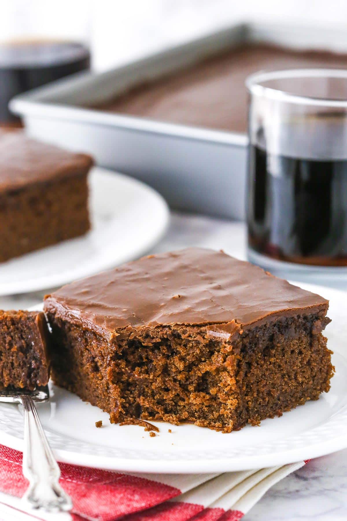 A slice of Coca Cola cake with a bite removed on a fork.