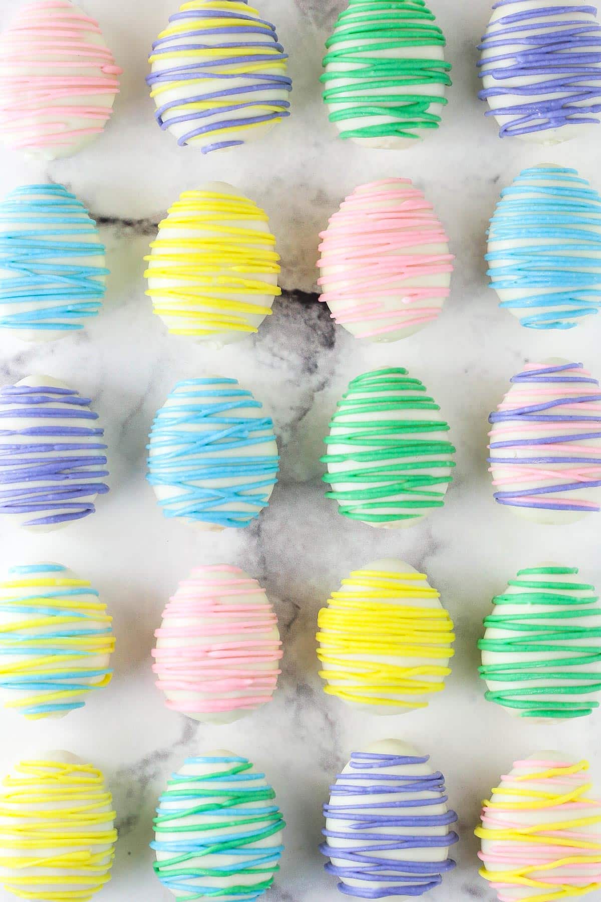 Rows of Easter egg Oreo cookie balls on a marble counter top.