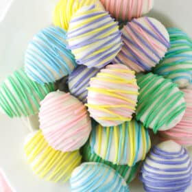 Easter egg Oreo cookie balls stacked on a white plate.